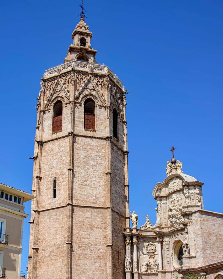 Torre del Miguelete y fachada de la Catedral de Valencia vistas desde la plaza de la Reina, con turistas caminando al atardecer