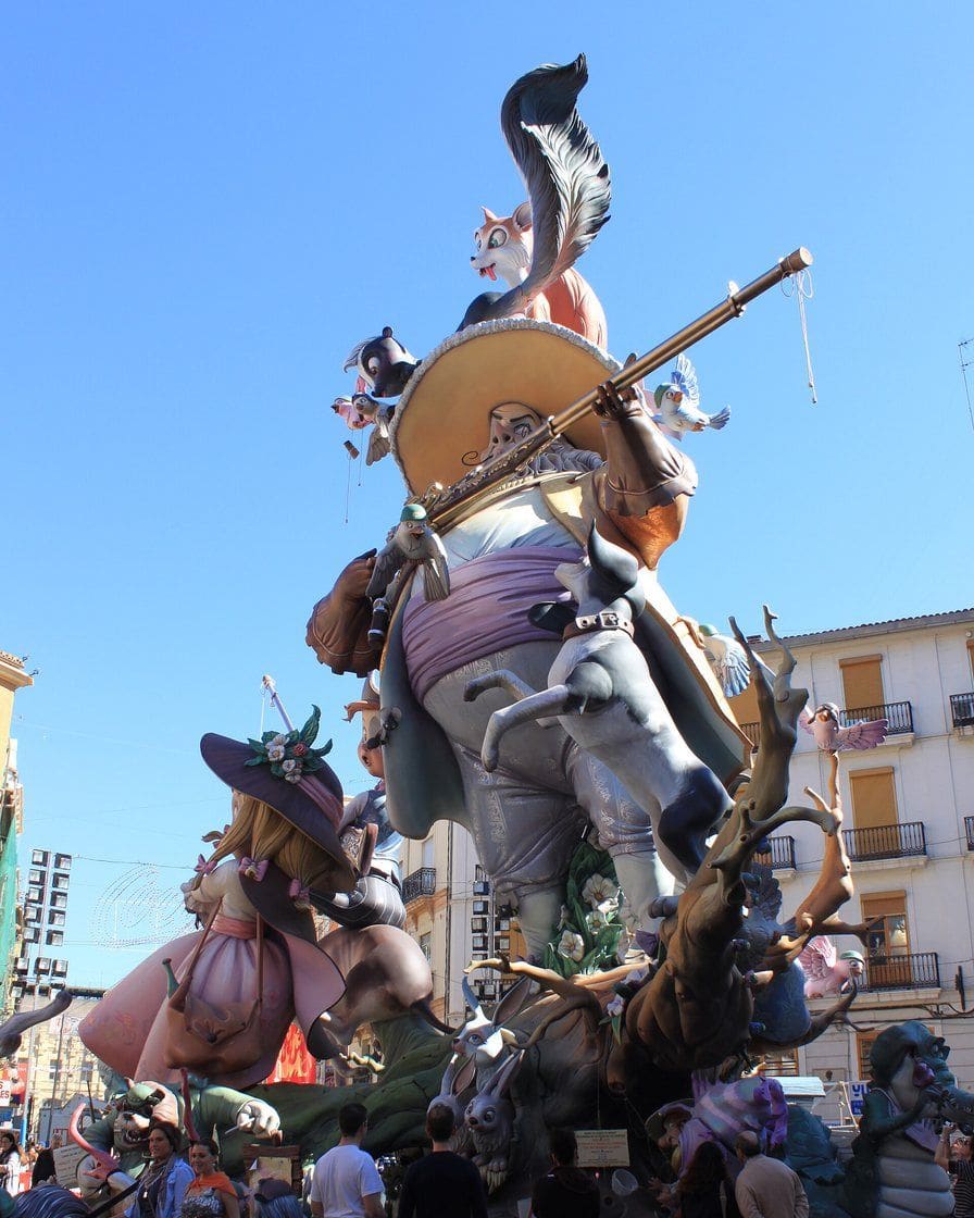 Falla monumental de Sección Especial junto a la Estación del Norte de Valencia, con figuras satíricas pintadas y visitantes rodeando el vallado