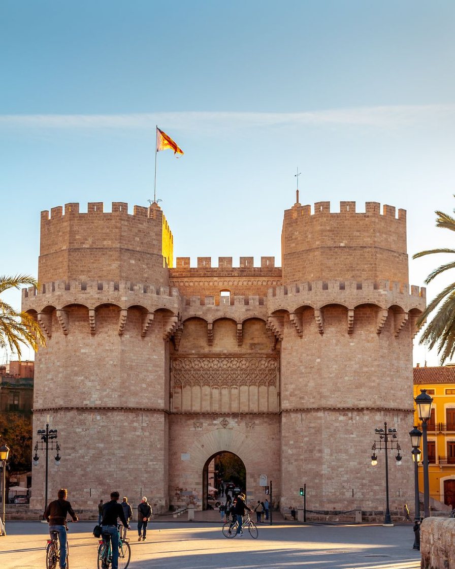 Torres de Serranos de Valencia iluminadas de noche con una multitud a sus pies durante la Crida que abre las Fallas