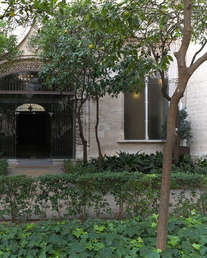 Patio interior de los Naranjos de la Lonja de la Seda de Valencia, con árboles de naranjo y la fachada gótica de piedra alrededor