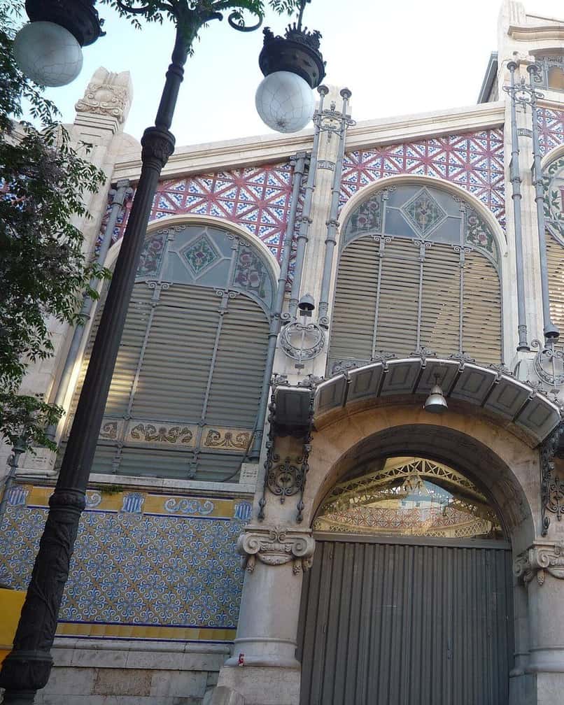 Banchi di frutta e verdura sotto la cupola modernista del Mercato Centrale di Valencia un sabato mattina, con clienti che fanno la spesa