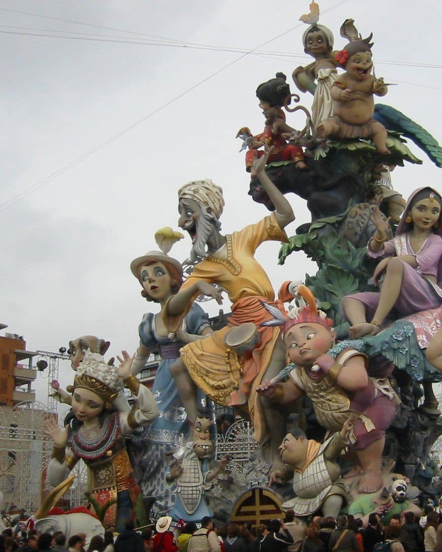 Falla de gran tamaño en el barrio de Campanar en Valencia, con figuras de cartón piedra pintadas de colores y vecinos fotografiando de noche