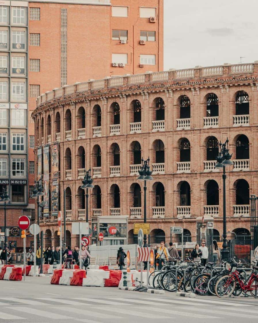 Facciata neomudéjar in mattoni dell'arena di Valencia accanto alla Estación del Norte, con archi e pubblico sul marciapiede