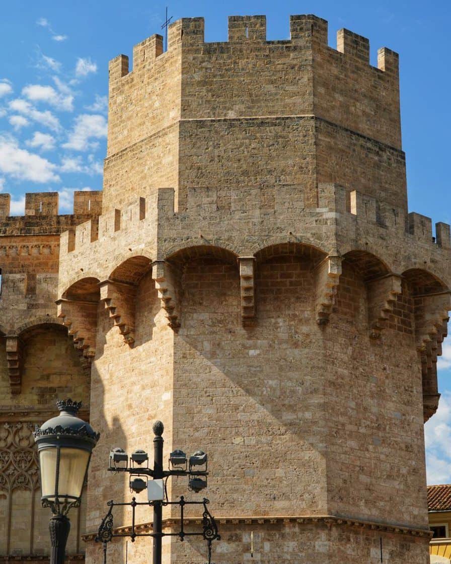 Torres de Serranos de Valencia iluminadas de noche, con la fallera mayor en lo alto de la torre y una multitud reunida abajo durante la Crida